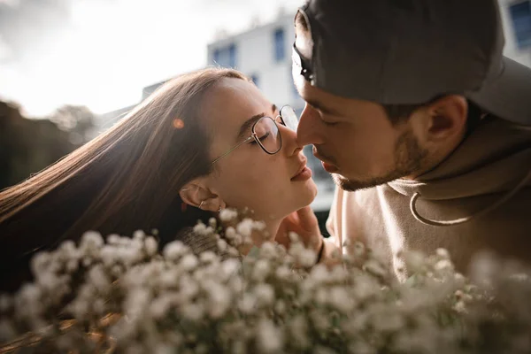 若い女性と男にキスの頭の美しい肖像画 手前の花びらの花束 — ストック写真