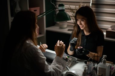 Manikürcüye manikürcüden manikür yaptıran muhteşem bir kadın. Güzellik endüstrisi, çivi ve el bakımı konsepti.