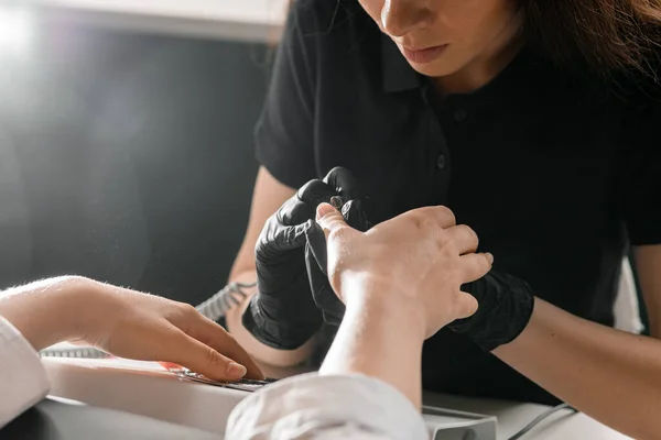 Manikiurzystka Czarnych Rękawiczkach Trzyma Profesjonalne Urządzenie Usuwania Naskórka Delikatnie Oblewa — Zdjęcie stockowe