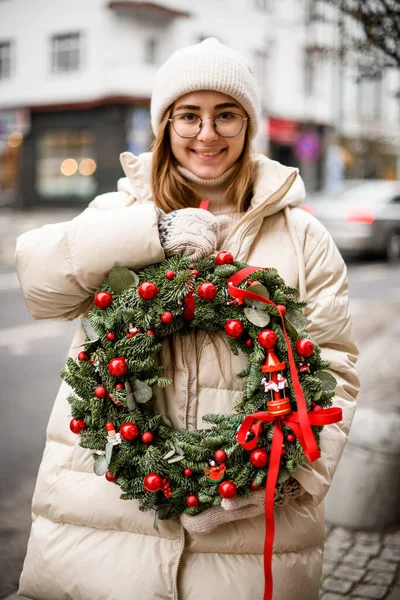 Νεαρή Όμορφη Ευτυχισμένη Γυναίκα Κρατά Στα Χέρια Της Χριστουγεννιάτικο Στεφάνι — Φωτογραφία Αρχείου