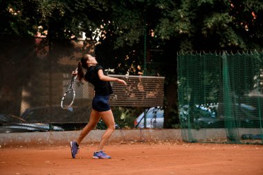 Tenis antrenmanı. Tenis raketi olan güzel bir bayan oyuncu. Açık tenis kortunda oynuyor. Açık hava tenis antrenmanı..