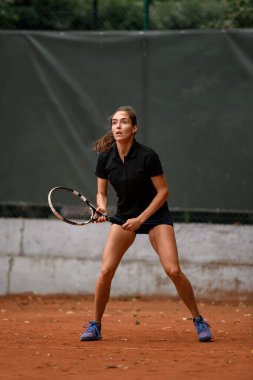 Raketiyle tenis topuna vurmaya hazır güzel ve enerjik bayan tenisçi. Açık tenis kortunda antrenman. Açık hava tenis antrenmanı..