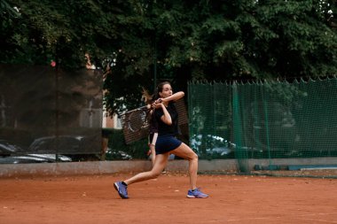 Tenis raketiyle kendisine doğru uçan bir tenis topuna çarpmaya hazır bir bayan tenisçinin görüntüsü. Açık hava tenis antrenmanı..