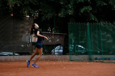 Sırtında tenis raketi olan aktif kadın tenisçinin yan görüntüsü. Açık hava tenis antrenmanı..