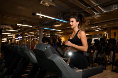 Spor salonunda koşu bandında koşan güzel kaslı atletik kadın manzarası. Kardiyo eğitimi. Sağlıklı yaşam tarzı