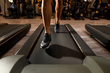 Koşu bandının önü ve spor ayakkabılarıyla koşan kadın atletik bacakları. Kardiyo eğitimi. Sağlıklı bir yaşam tarzı. Kesilmiş fotoğraf