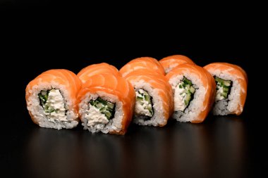 Close-up of Philadelphia sushi rolls with salmon, cucumber, avocado, cream cheese. On dark background. Sushi menu. Japanese food.