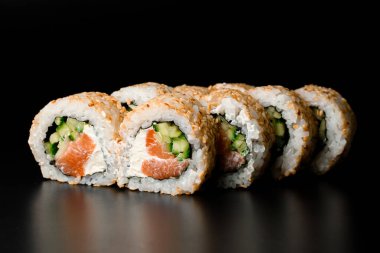 Sushi rolls california with smoked salmon, cream cheese, cucumber, sesame seeds on dark background. Japanese oriental cuisine. Sushi menu.