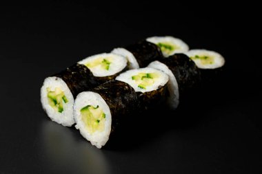 classic vegetarian kappa maki sushi rolls with fresh cucumbers and rice wrapped in nori on dark background