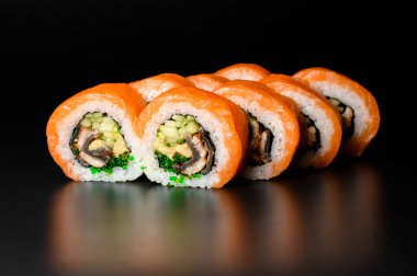 tasty Philadelphia sushi rolls with rice, salmon, shrimp, eel, cucumber, avocado, tobiko caviar, nori sauce and Philadelphia cheese