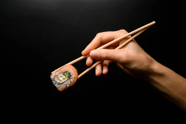 Side View Philadelphia Roll Hand Holding Bamboo Chopsticks Dark Background — Stok fotoğraf