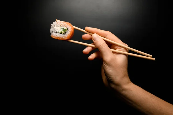 Female Hand Accurate Holding Philadelphia Maki Roll Bamboo Chopsticks Dark — Stok fotoğraf