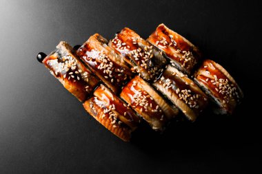 Top view on tasty Philadelphia sushi rolls with rice, salmon, eel, cucumber, avocado, tobiko caviar, nori, Philadelphia cheese, soya sauce and sesame