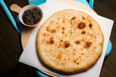 view on round lavash with seasonings on black table. Traditional tasty baked pita bread. Pizza base.