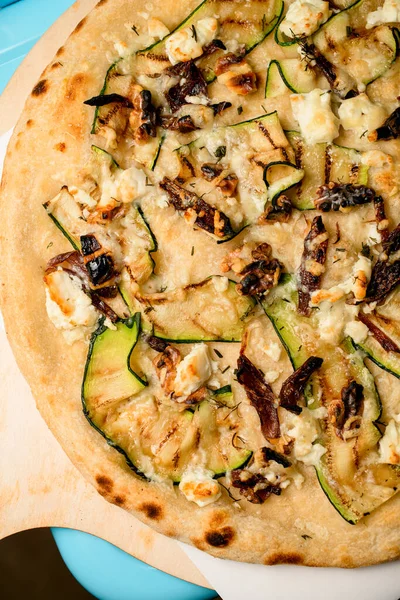 Close-up part of hot vegetarian vegetable pizza with mushrooms walnuts and zucchini slices. Top view