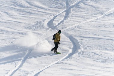 Active male freerider on a snowboard masterfully descends an off-piste on fresh snow in Gudauri Georgia. Good winter day, ski season