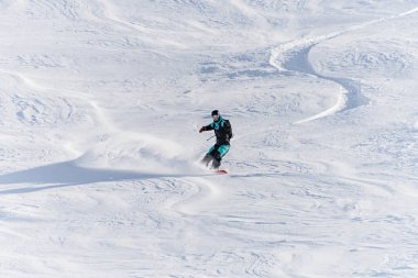 Freerider on snowboard ride down off-piste in deep fresh snow in Gudauri Georgia. Good winter day, ski season