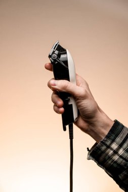 Close-up side view of electric hair clipper in male hand. Modern professional clipper for hairdressers. Barber shop.