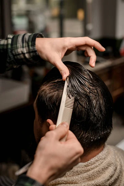 stock image Close-up view of barber hands accurate combs wet male hair and make new style for client. Stylish bearded man getting trendy haircut and hairstyle. Concept of hairdressing and shave.