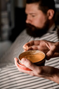 Selective focus on jar with hair gel for styling in male hands. Beauty industry. Barbershop concept.