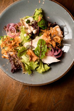 Mantarlı salata ve taze yeşil ve mor marul yaprakları ve havuç ve pancar yaprakları ve tabakta kırmızı soğan halkaları.