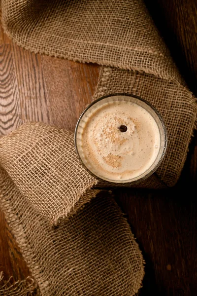 木製テーブルの上にコーヒー豆で装飾されたおいしい泡のコーヒーカクテルとガラスのトップビュー — ストック写真