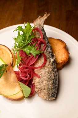 Soğan ve limonla süslenmiş bol yağda kızartılmış balık ve kızarmış ekmekli tost tabağı.