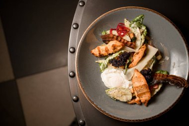 En üst tabakta leziz yemekler haşlanmış yumurtalar, yeşil marul, kızarmış pastırma ve tavuk.