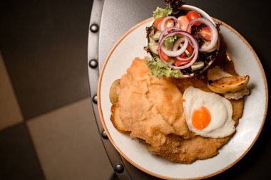 Üst tabakta domuz pirzolası, kızarmış yumurta, patates ve salata..