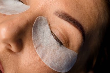 Gözünün altında tek kullanımlık kağıt yama olan kadın yüzü. Kirpik uzatma prosedürü kavramı