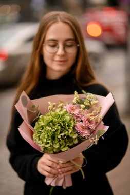 Bir buket pembe kasımpatı ortancası ve kadın ellerine sarılı beyaz hipsofila. Sonbahar sunucuları karışır