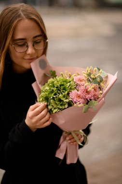 Zarif bir buket pembe kasımpatı ortancası ve kadın ellerine sarılı beyaz hipsofila. Sonbahar sunucuları karışır