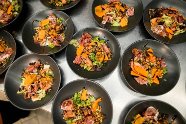 Jamonlu salata, salata karışımı, peynir, fındık ve terijaki soslu siyah tabaklar. Sağlıklı yemek, keto diyeti, diyet öğle yemeği konsepti..