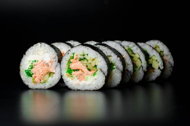 Ton balığı, krem peynir, salatalık, pirinç, yeşil buzağı ve siyah üzerine izole edilmiş nori. Japon yemeği..