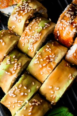 Yılanbalığı, avokado, teriyaki sosisi, taze sebze ve susamlı büyük suşi seti. Suşi karışımı.