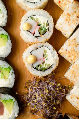 Tahta servis tahtasında Philadelphia peyniri, yengeç çubuğu, salatalık ve mikroyeşil ile iştah açıcı rulo. Dikey görünüm