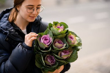 Gülümseyen genç kadın elinde güzel bir demet lahana buketi tutuyor. Dekoratif bitki