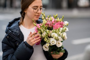 Çiçek açan çiçek buketi elinde krema, pembe ve sarı renkler içinde ellerinde bulanık arka planda