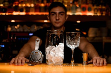 Alkolsüz ve alkolsüz kokteyl yapmak için gerekli ekipmanların olduğu tezgah. Arka planda bulanık barmenler silueti