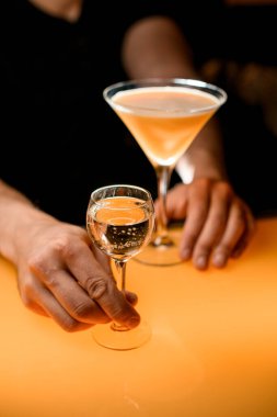 Barmen, tatlı şampanyayla birlikte bardak servis ediyor. Meyve suyuyla birlikte taze portakallı martini kokteyli tezgahın yanında duruyor.