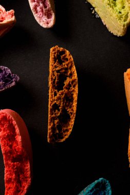 Makro fotoğraf siyah üzerine yarım badem kurabiyesine boyanmış lezzetli farklı renkler. Narin Fransız kurabiyeleri. Kurabiyeler kremaya dayanır.