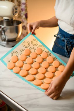 Kız pastacı, taze pişmiş makaron parçalarını silikondan kaldırıyor. Makaron yapma süreci.