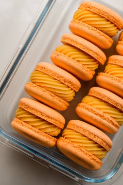 Renkli turuncu Fransız ya da mango ganashe soslu İtalyan badem kurabiyelerine yakından bakın. Ev yapımı tatlılar ile şeffaf cam form. Fırın kavramı