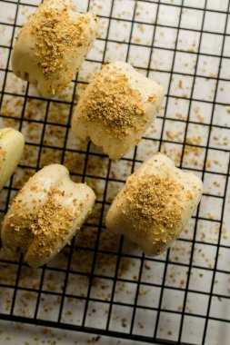 Beyaz çikolata ve metal şebekede kesilmiş fıstık ile süslenmiş taze fıstıklı kurabiyelerin yakın görüntüsü. Ev yapımı fırın konsepti