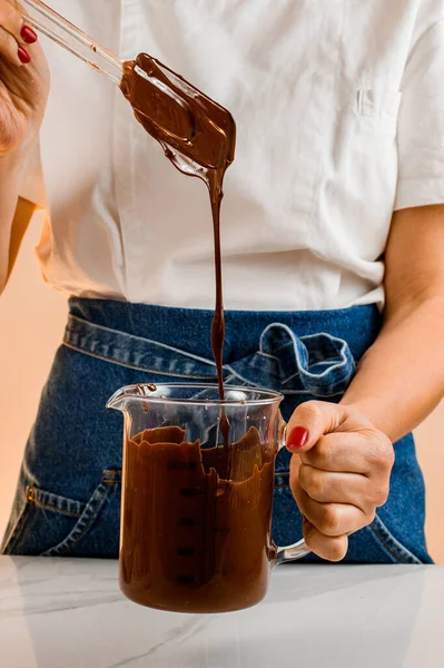 Perempuan Mencampur Coklat Cair Dan Kacang Dalam Cangkir Pengukuran Transparan — Stok Foto