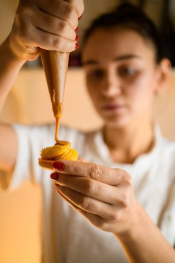 Aşçı kadın tatlı kremayı dikkatlice sıkıyor. Şekerleme poşetinden taze makarona kadar. Ev pastası konsepti