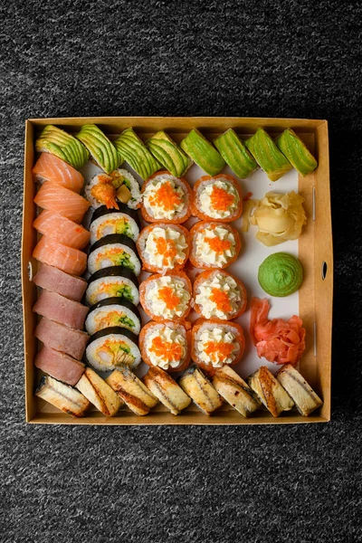 不同的寿司卷的顶部视图与鲑鱼 熏鱼在交货箱黑色背景 食物派递概念 — 图库照片