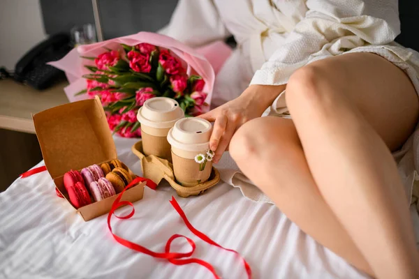 在女人的腿旁边放着新鲜咖啡和金银花甜点的托盘 早餐在床上的概念 床上放满了五彩缤纷的郁金香 浮动交付概念 — 图库照片