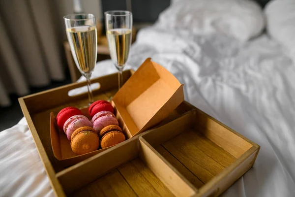 Two champagne glasses and box of assorted tasty macaroons sweets, blurred background. Female party concept.