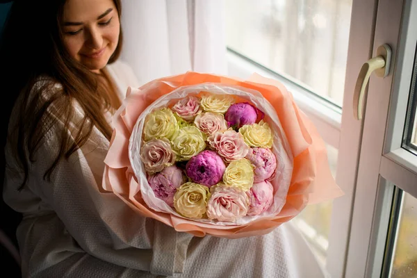잠옷을 소녀가 가까이에 포장지 로장식된 노란색 분홍색 꽃들로 아름다운 꽃다발을 — 스톡 사진